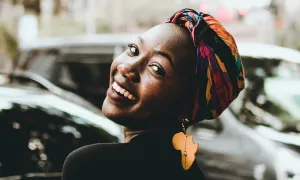 "a, smiling black female wearing an earring shaped like Africa"