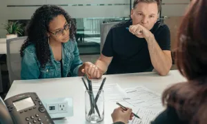 "a couple reviewing forms while talking to a government official"