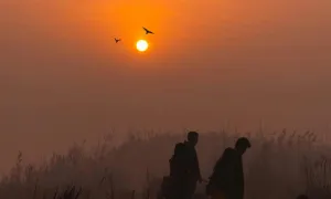 "two people walking across a hilly landscape at sunset"