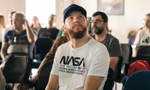 "man in a NASA shirt sitting in a public forum"