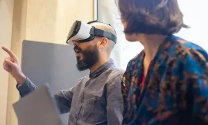 "a man wearing a VR headset and talking to another person"